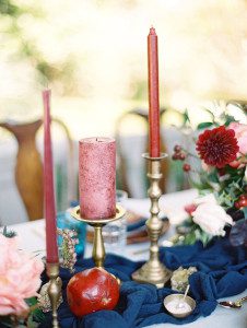 Burgundy pillar and taper candles on blue table runner