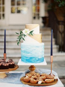 Wedding cake with the base layer in a blue watercolor wash. Top layers are dipped in edible gold.