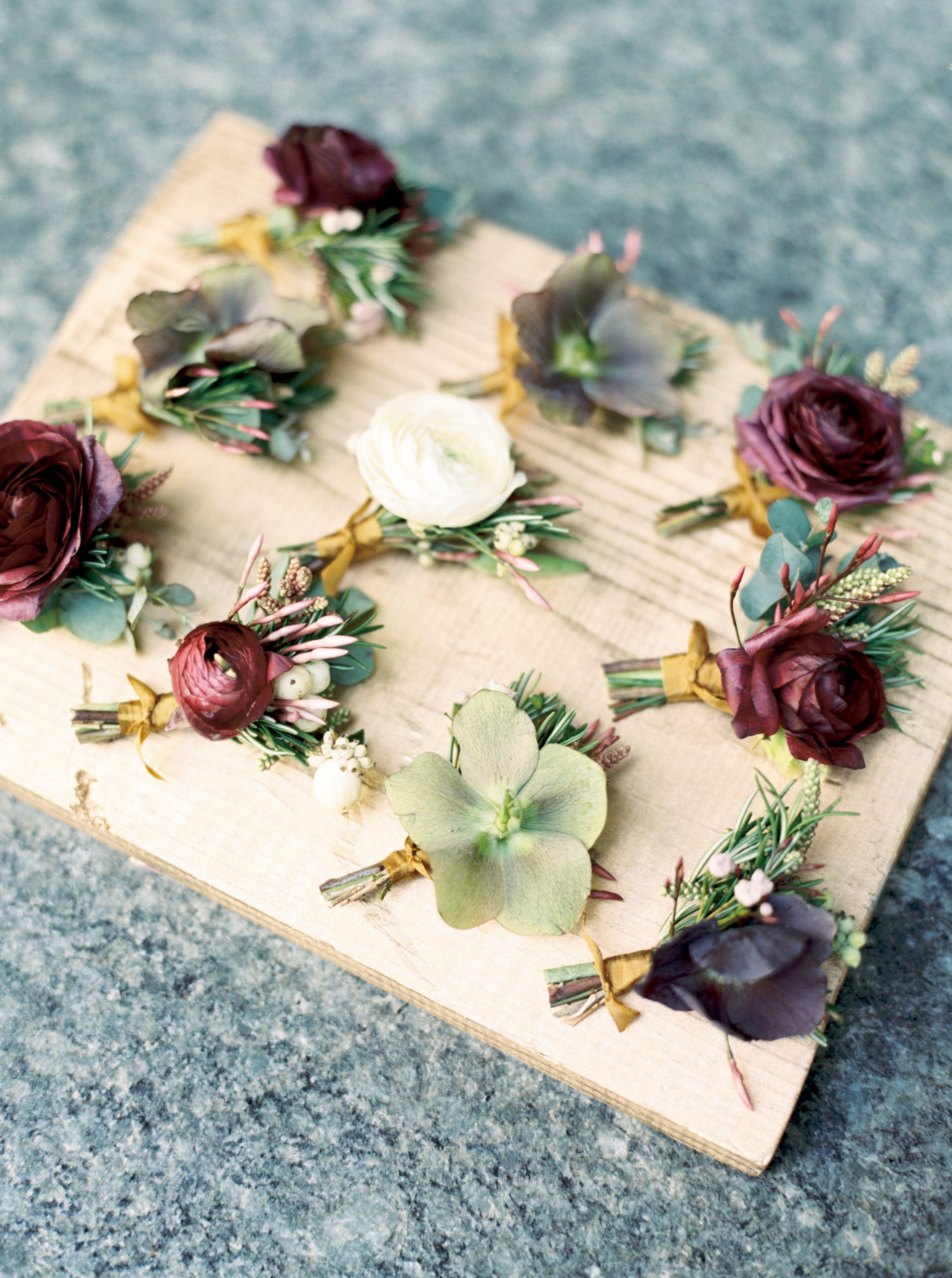 green and purple hellebore boutonnieres styled on gold wood