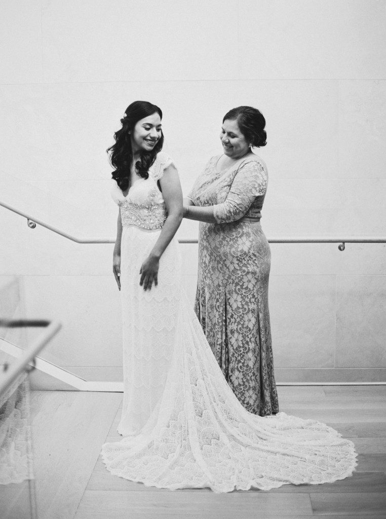 Mother of the bride helping bride into her dress at a Nasher Sculpture Center wedding