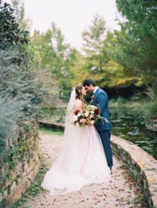 Bride and groom embrace by pond