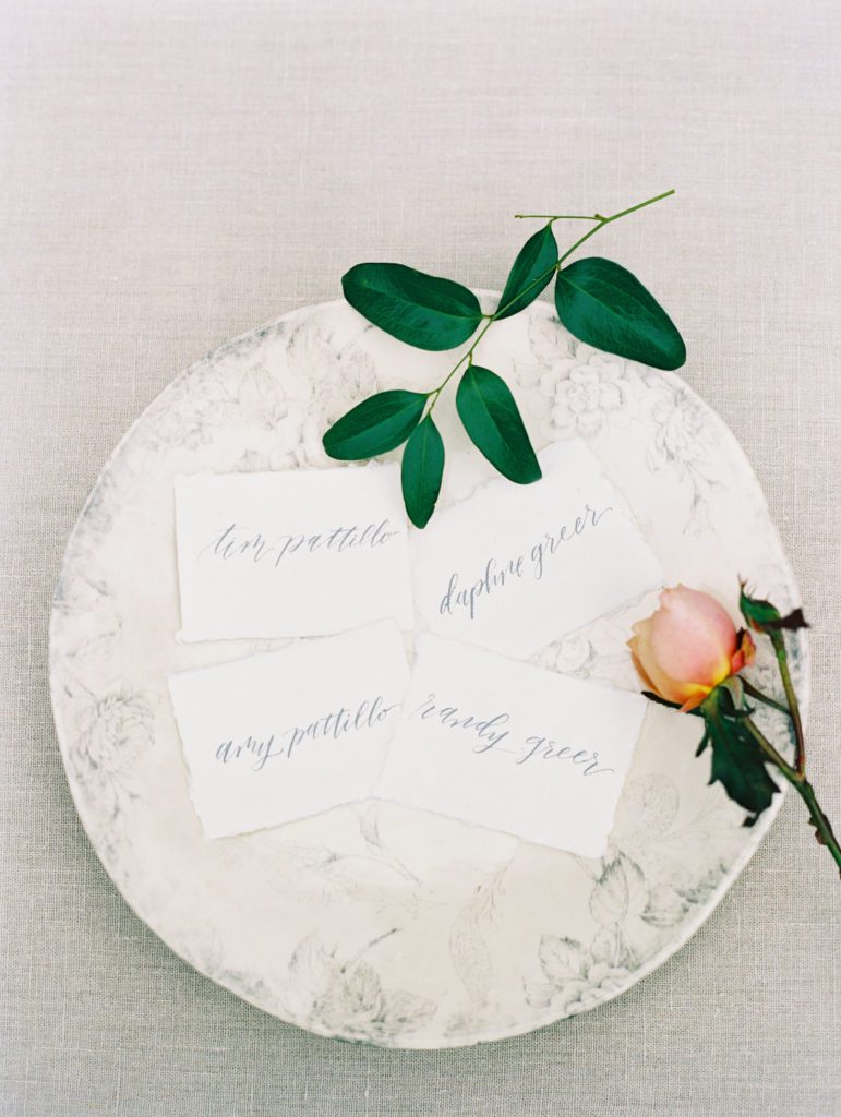 Handwritten place cards styled on floral plate