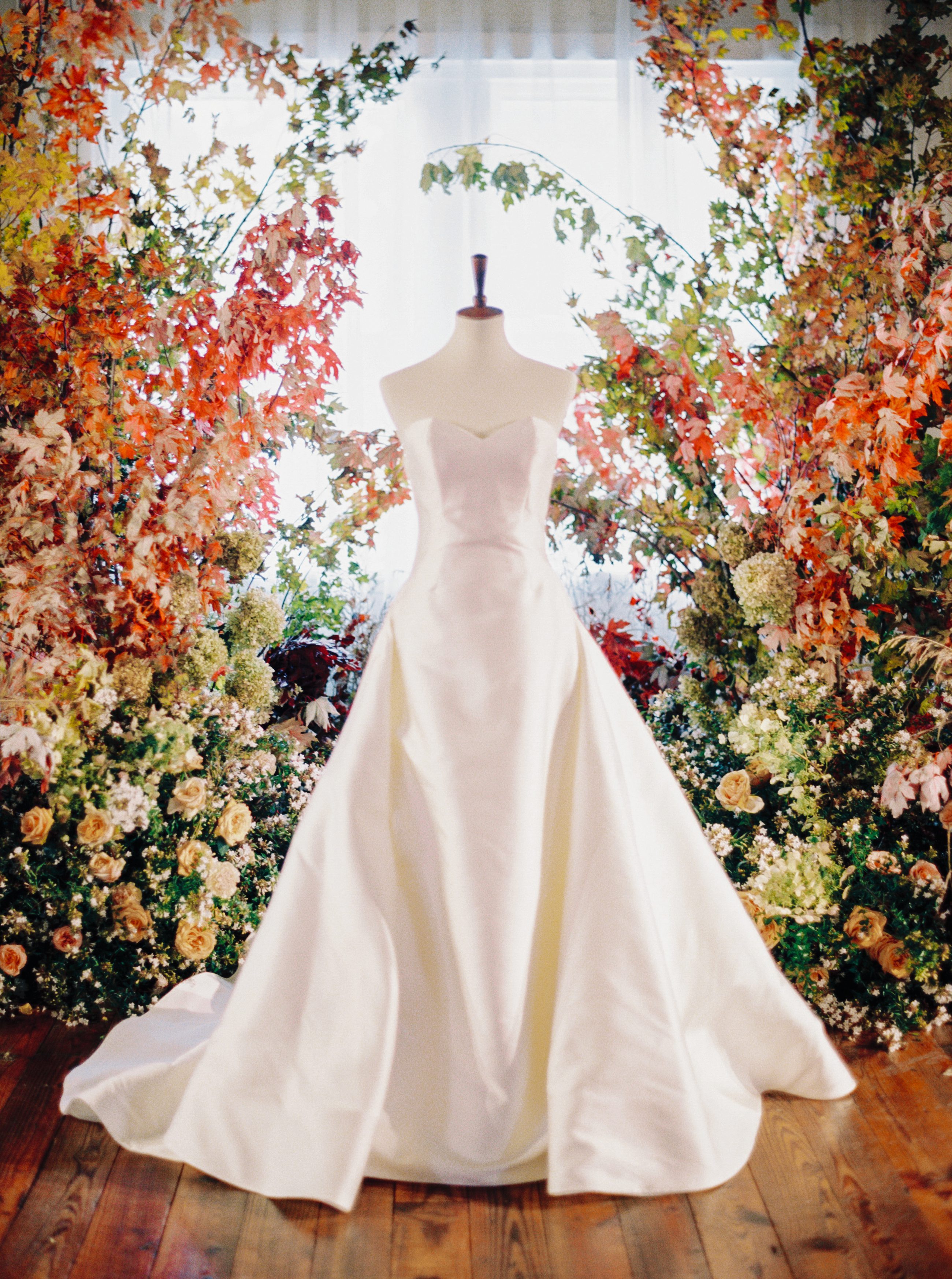 wedding gown in front of a fall leaves wedding ceremony altar at a Brik Venue wedding in Fort Worth Texas planned and designed by Fort Worth wedding planner Birds of a Feather Events